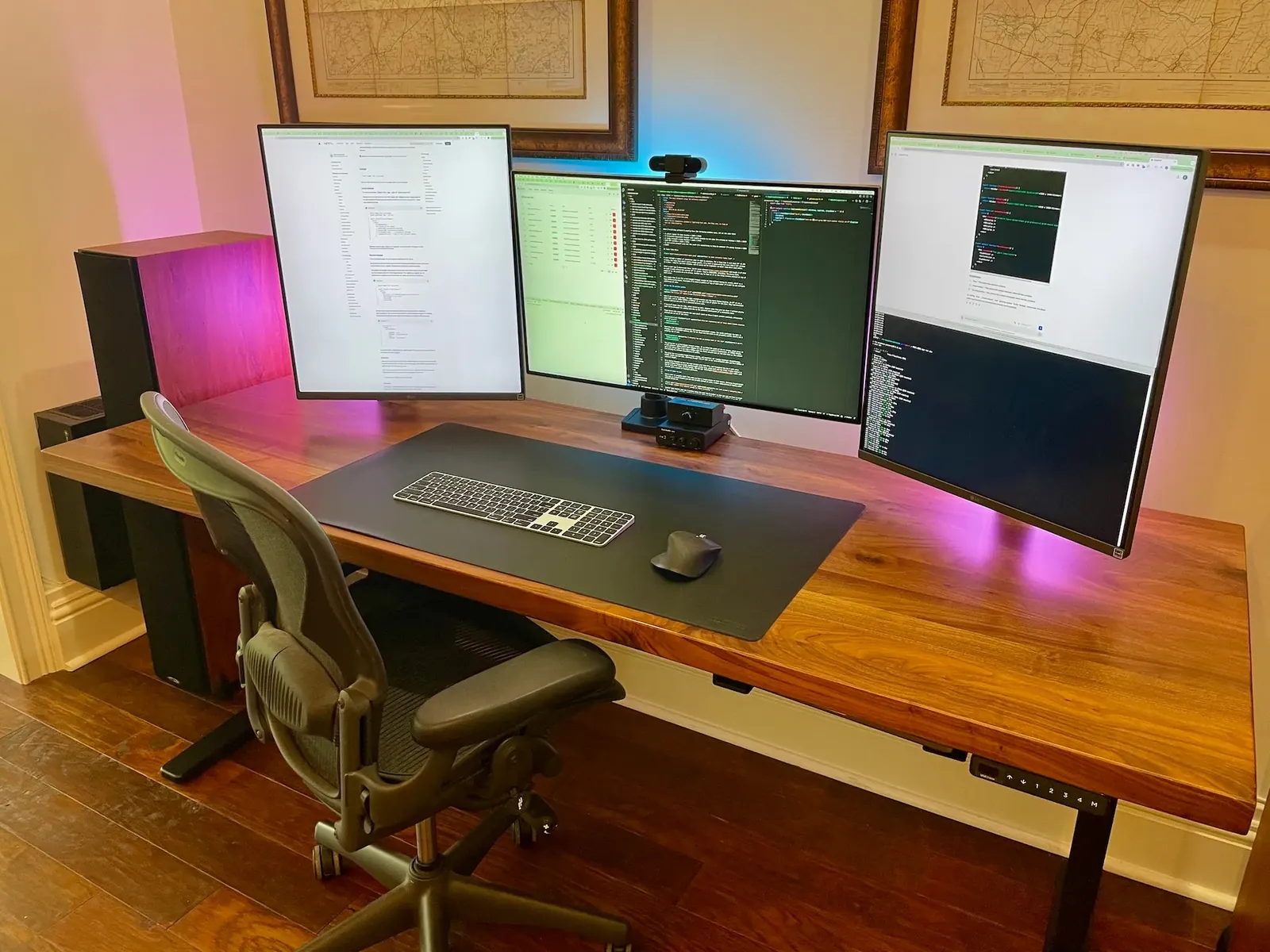 De werkplek van Rayan: drie schermen met code op een houten bureau